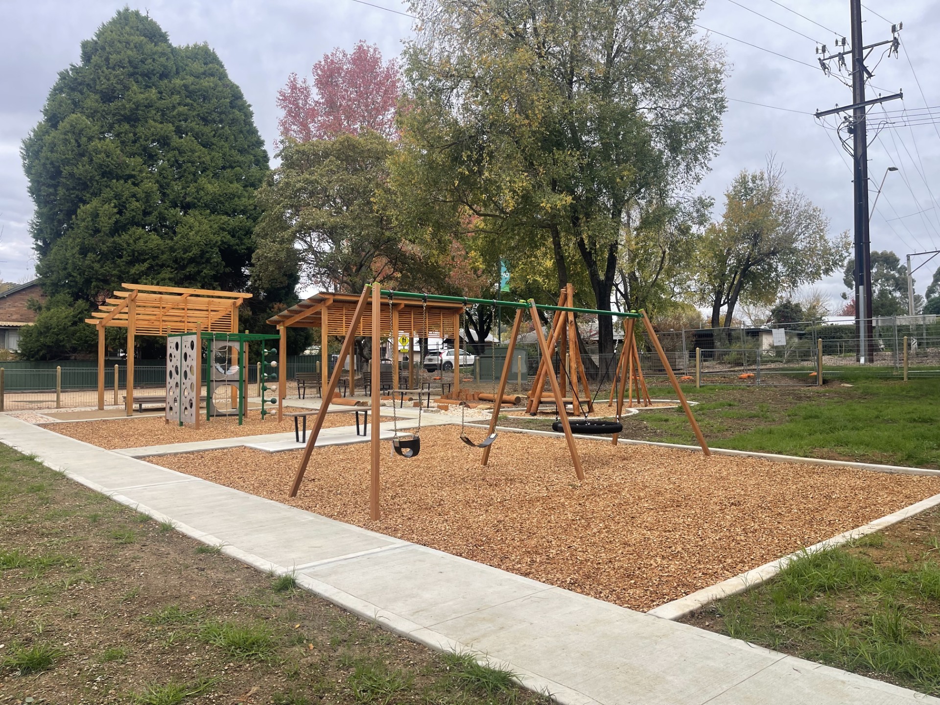 play equipment with bark chips and a concrete footpath